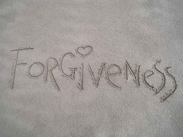 Forgiveness in den Sand geschrieben